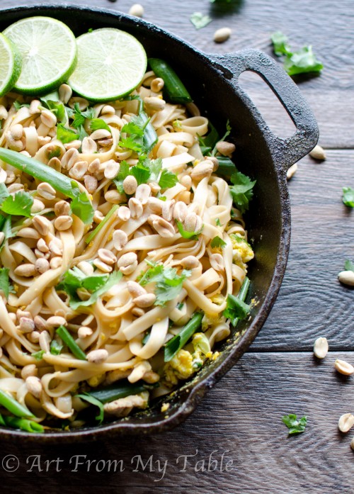 Healthy vegetable pad thai in a cast iron pan, garnished with peanuts and cilantro.