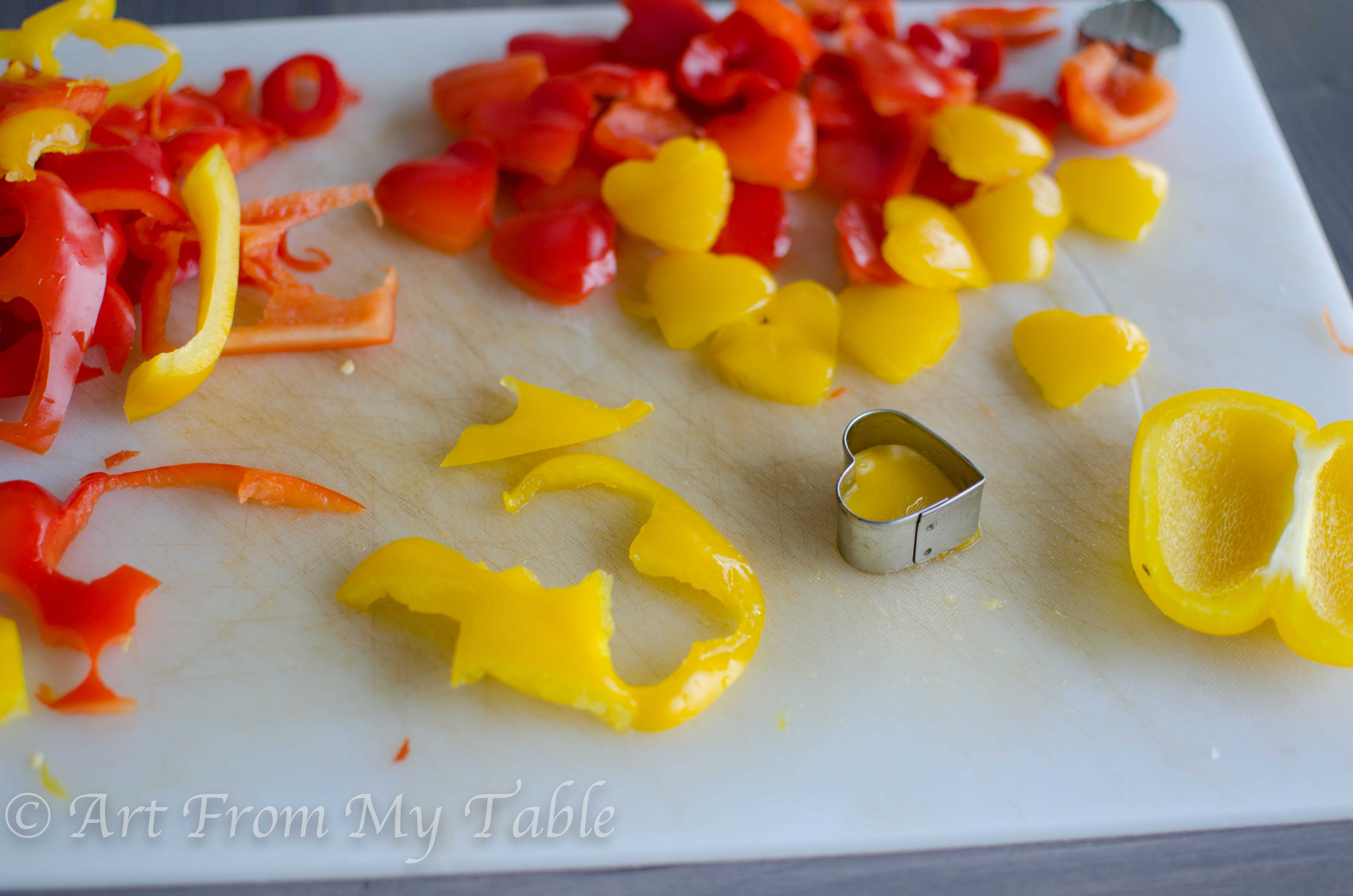 Bell peppers being cut into hears with a cookie cutter to make a healthy valentine snack.