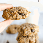 hand holding a breakfast cookie in focus with a stack of breakfast cookies in the background