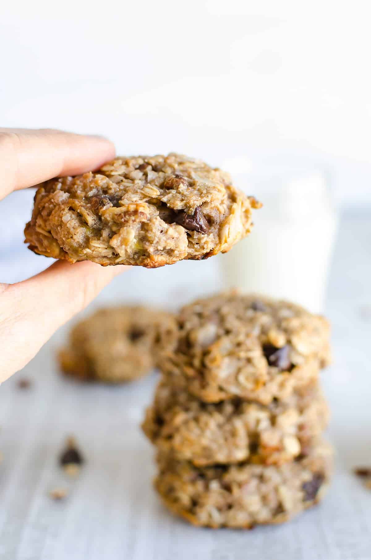 hand holding a breakfast cookie in focus with a stack of breakfast cookies in the background