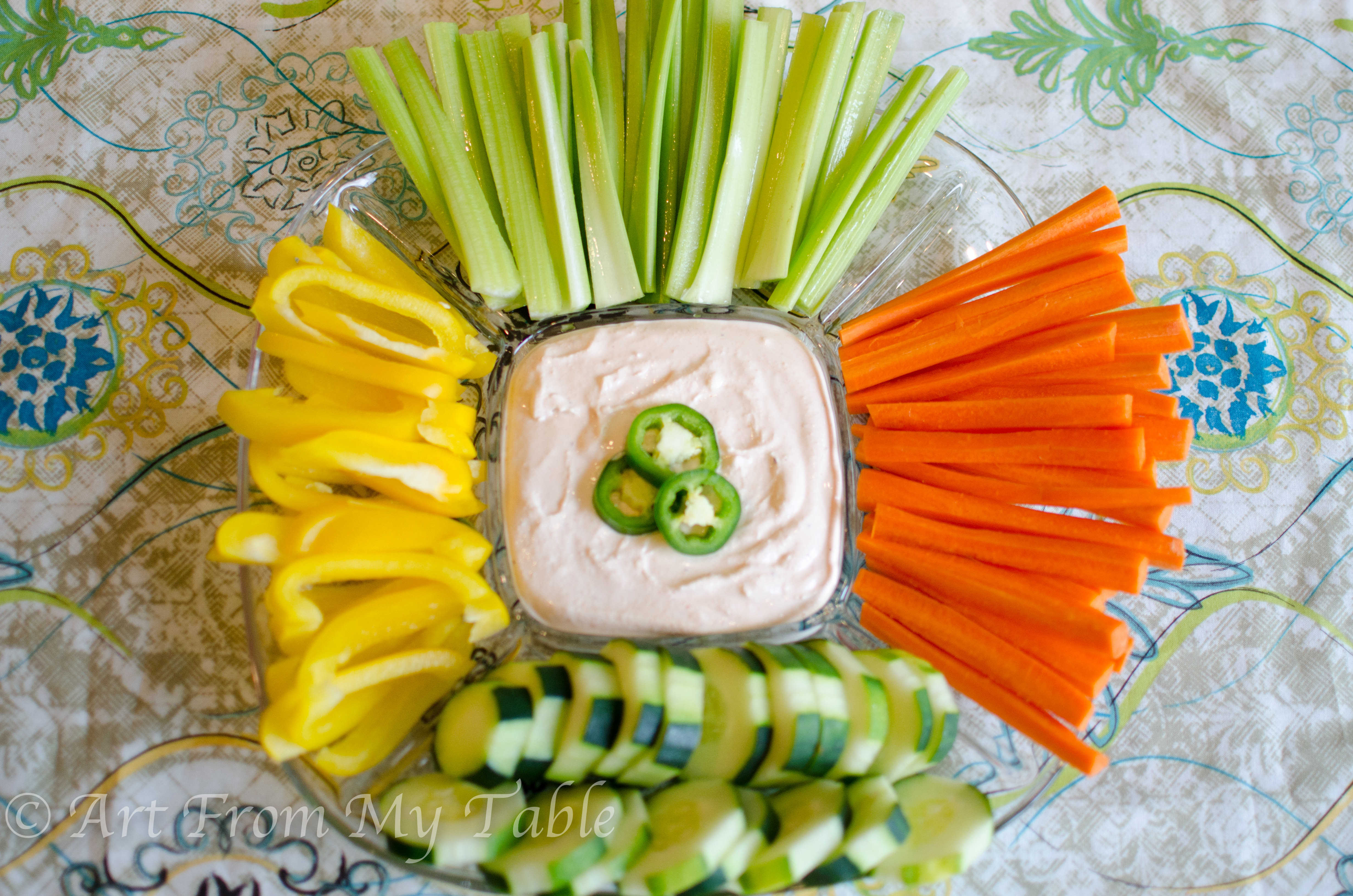 Veggie tray with jalapeño yogurt dip, garnished with fresh jalapeños.