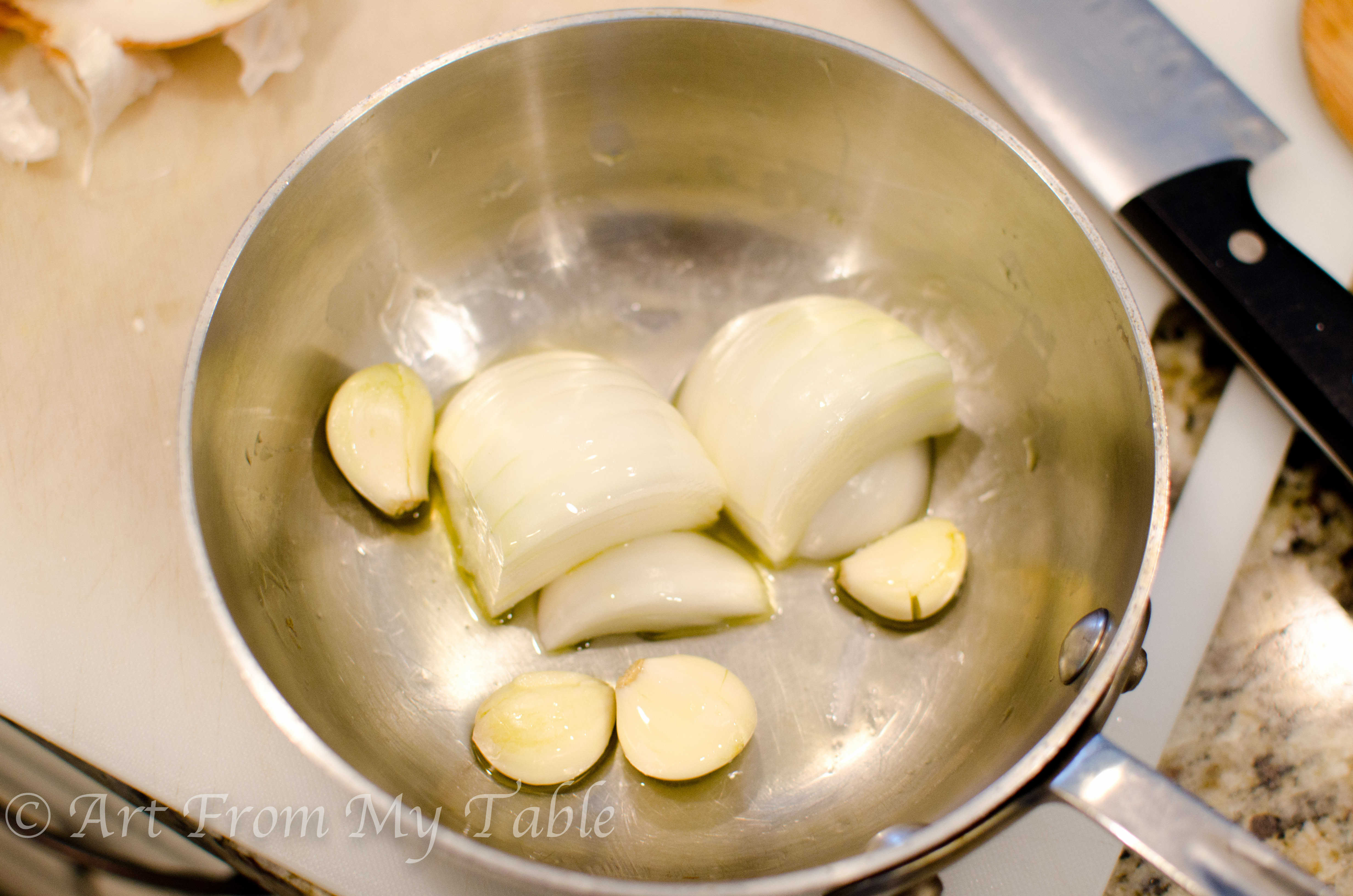 Onion halves and whole garlic in a pan before roasting.