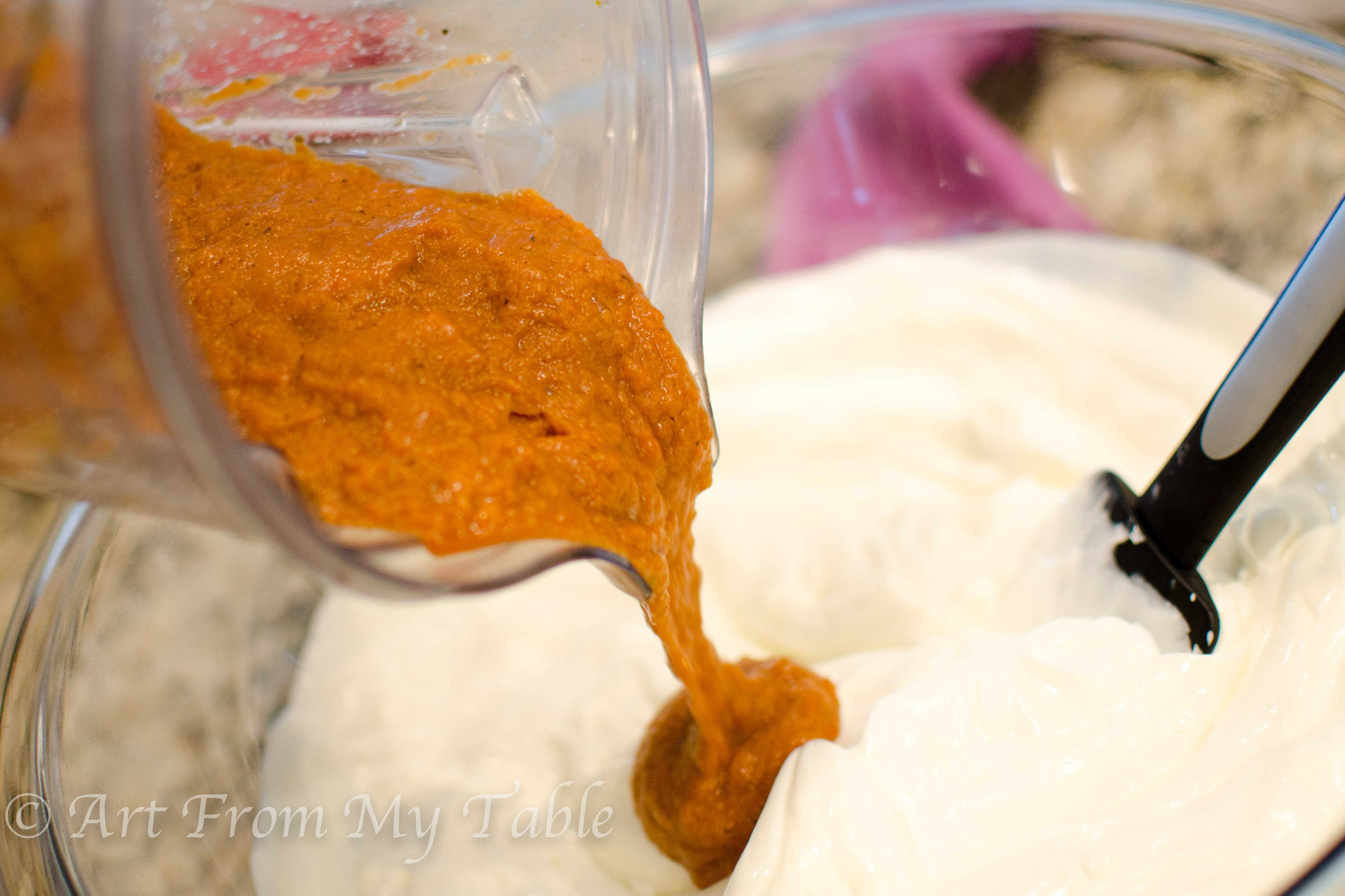 pureed vegetables being poured into a big bowl of yogurt and cream cheese.
