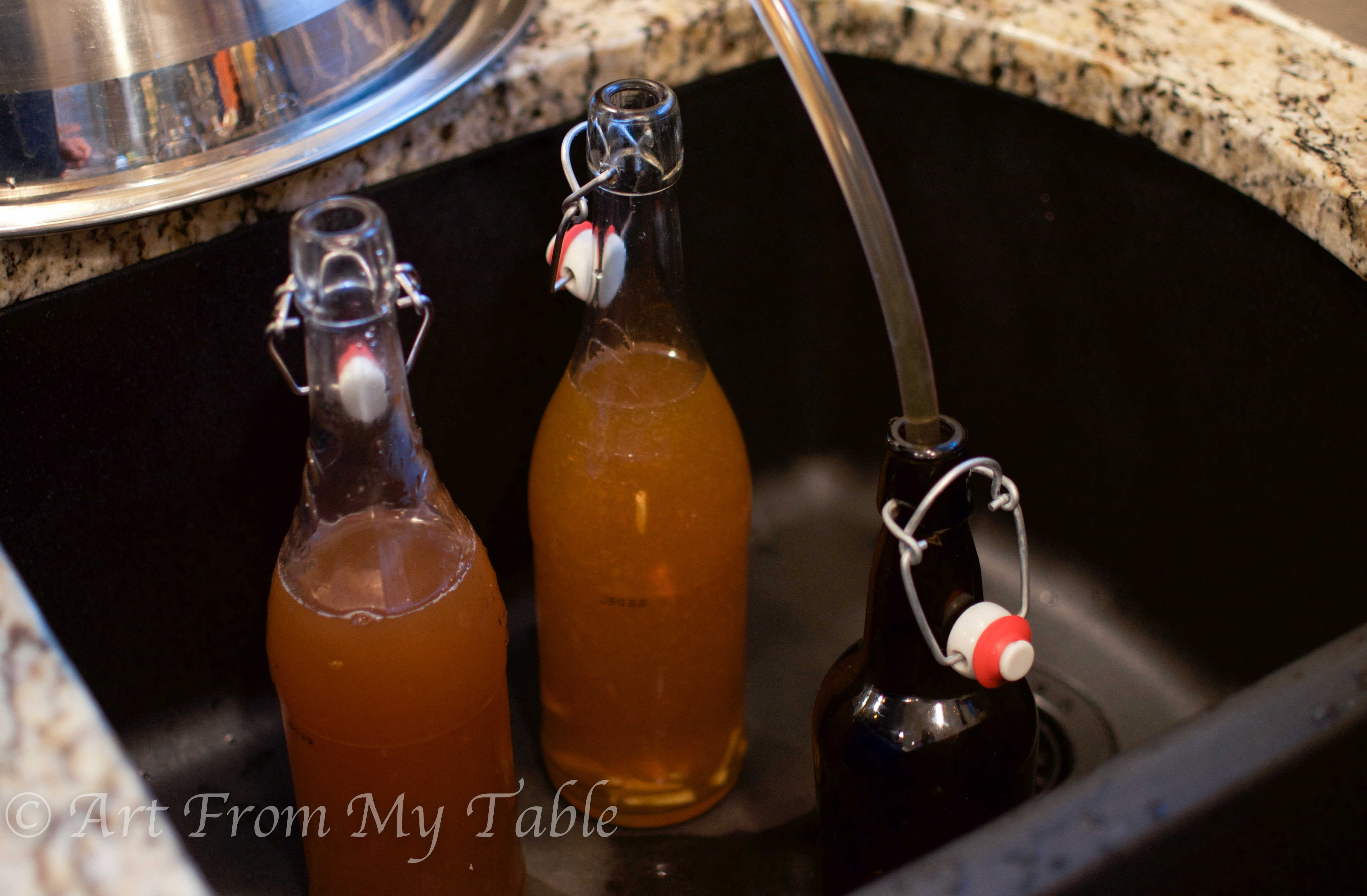 Closer image of Kombucha tea being siphoned into bottles. 