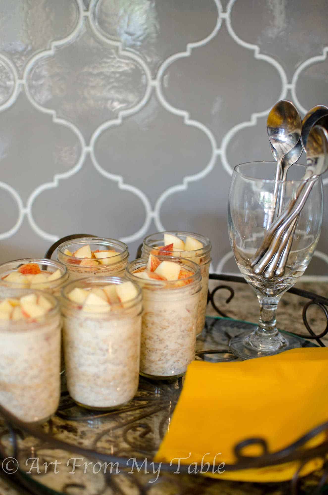 Overnight oats with apples and peanut butter served in pint sized jars on a serving tray. 