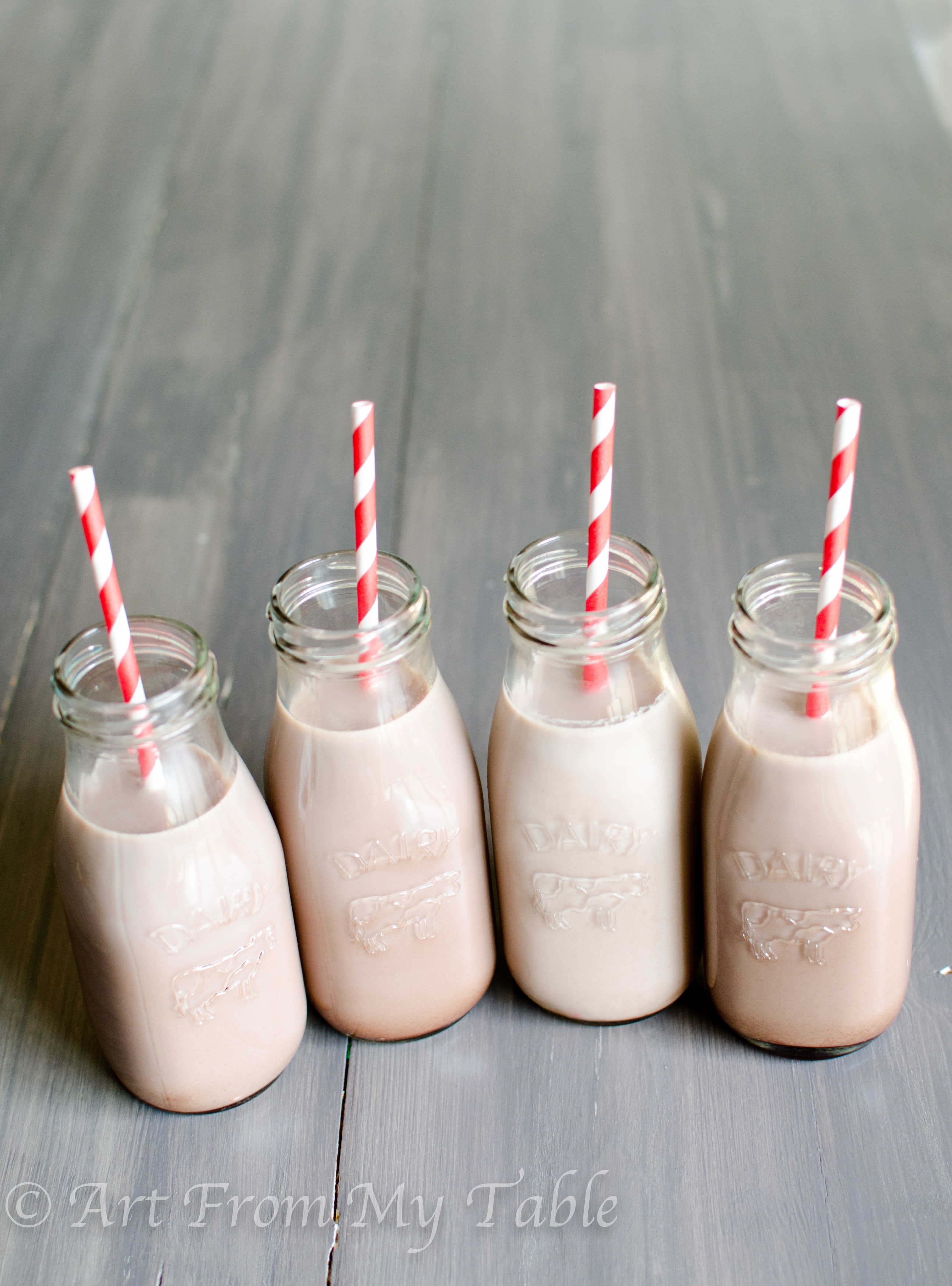 Four small glass milk bottles full of homemade chocolate milk.