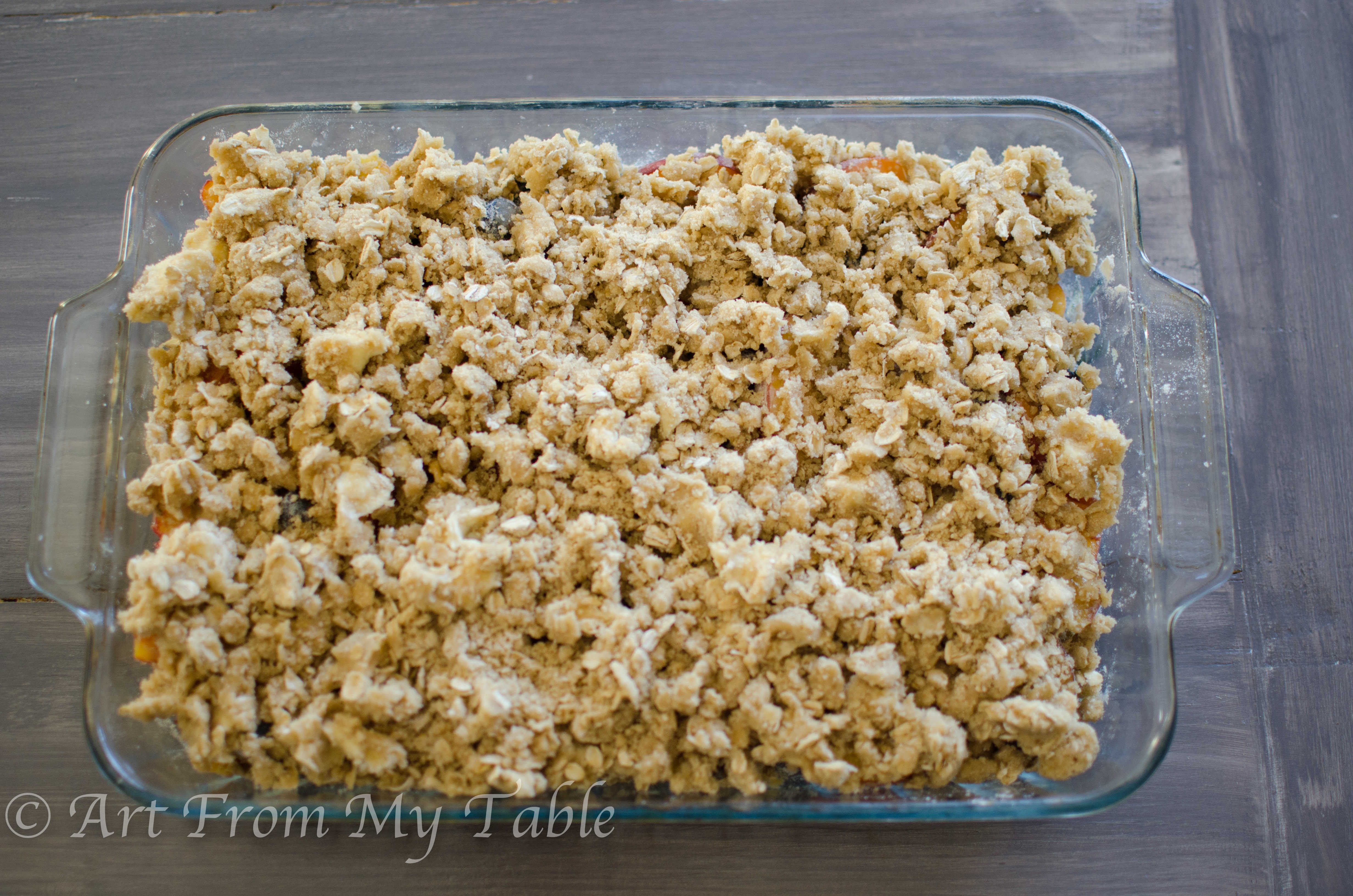 Blueberries and peaches with "crisp" topping ingredients over top, ready for the oven.