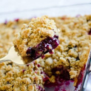 baked blueberry peach crisp being scooped from pan