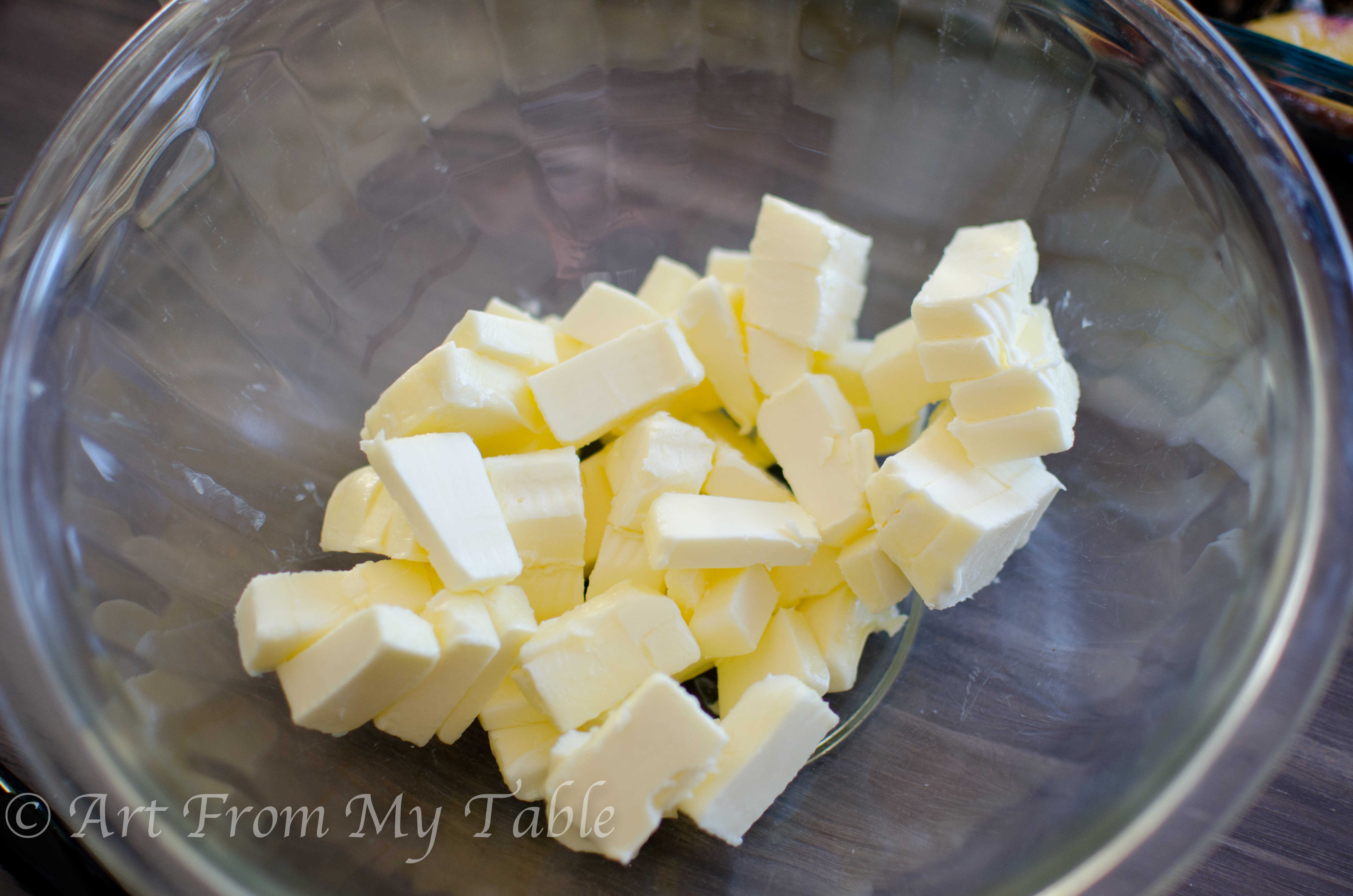 2 sticks of butter cut into cubes in a glass bowl.