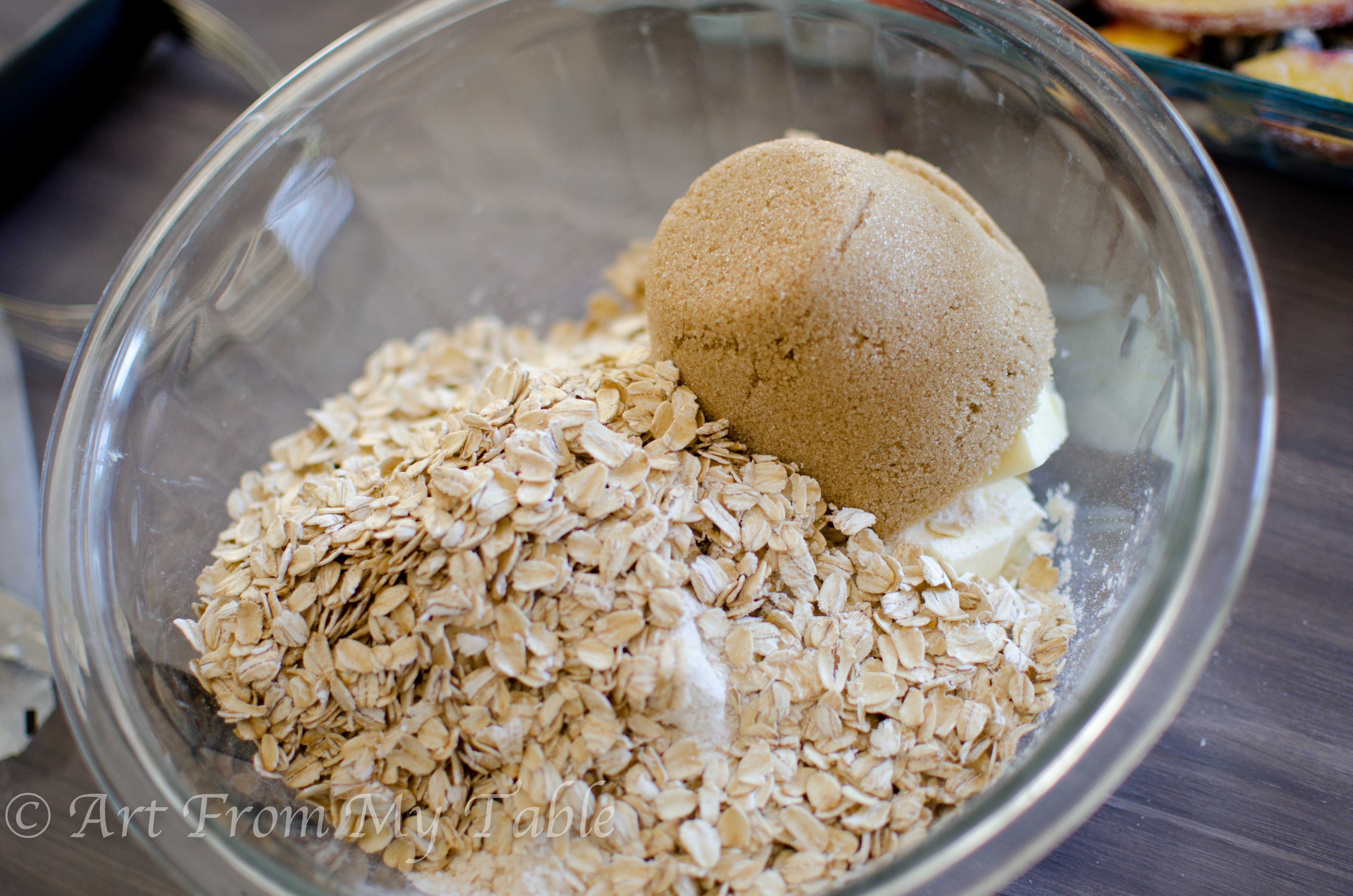 Butter, flour, brown sugar and oatmeal in a glass bowl.