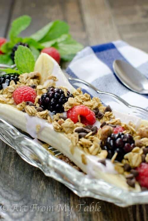 Healthy banana split with yogurt, berries, granola and chocolate chps.
