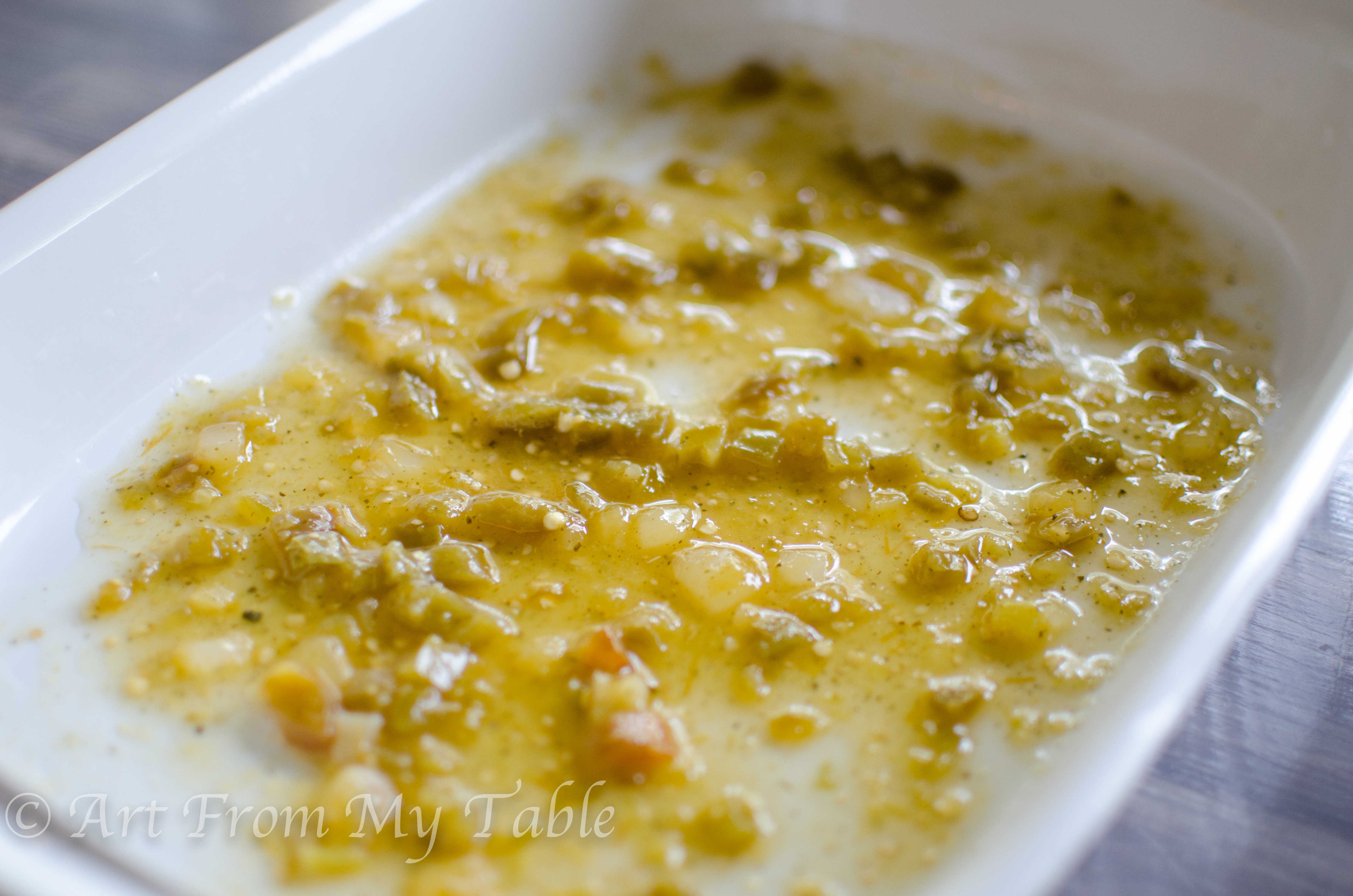White casserole dish with salsa verde spread on the bottom.