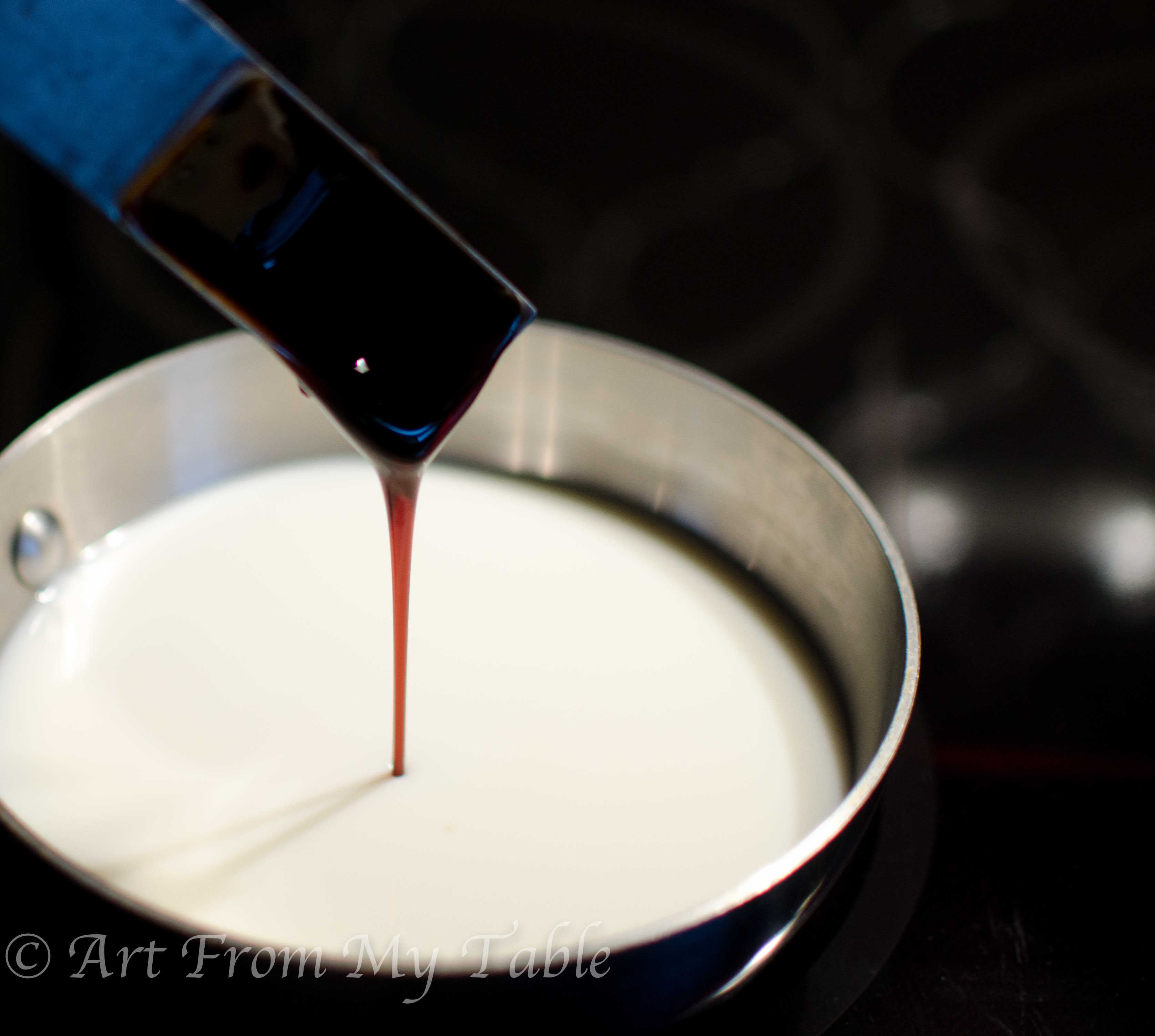 Pan of milk warming up with molasses being poured in.