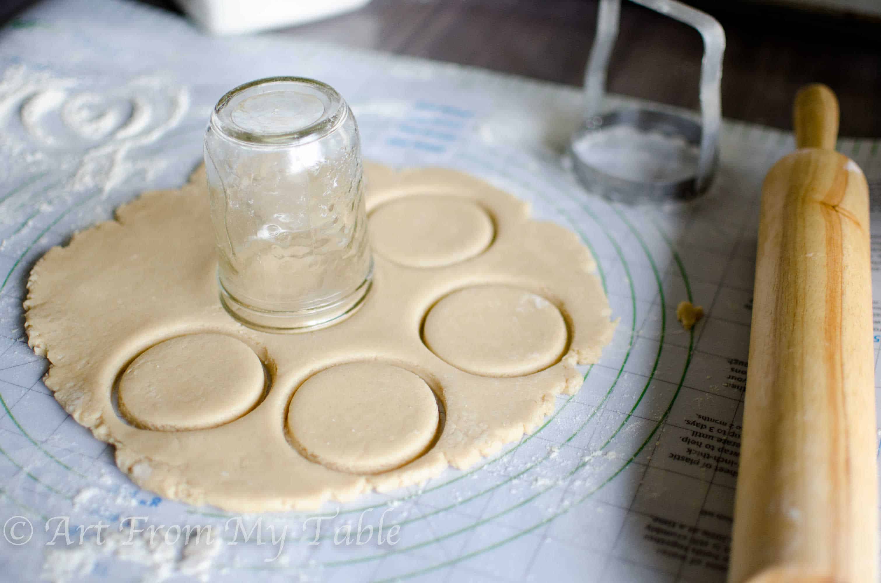Sugar cookie dough rolled into a disc using a mason jar upside down to cut circles.