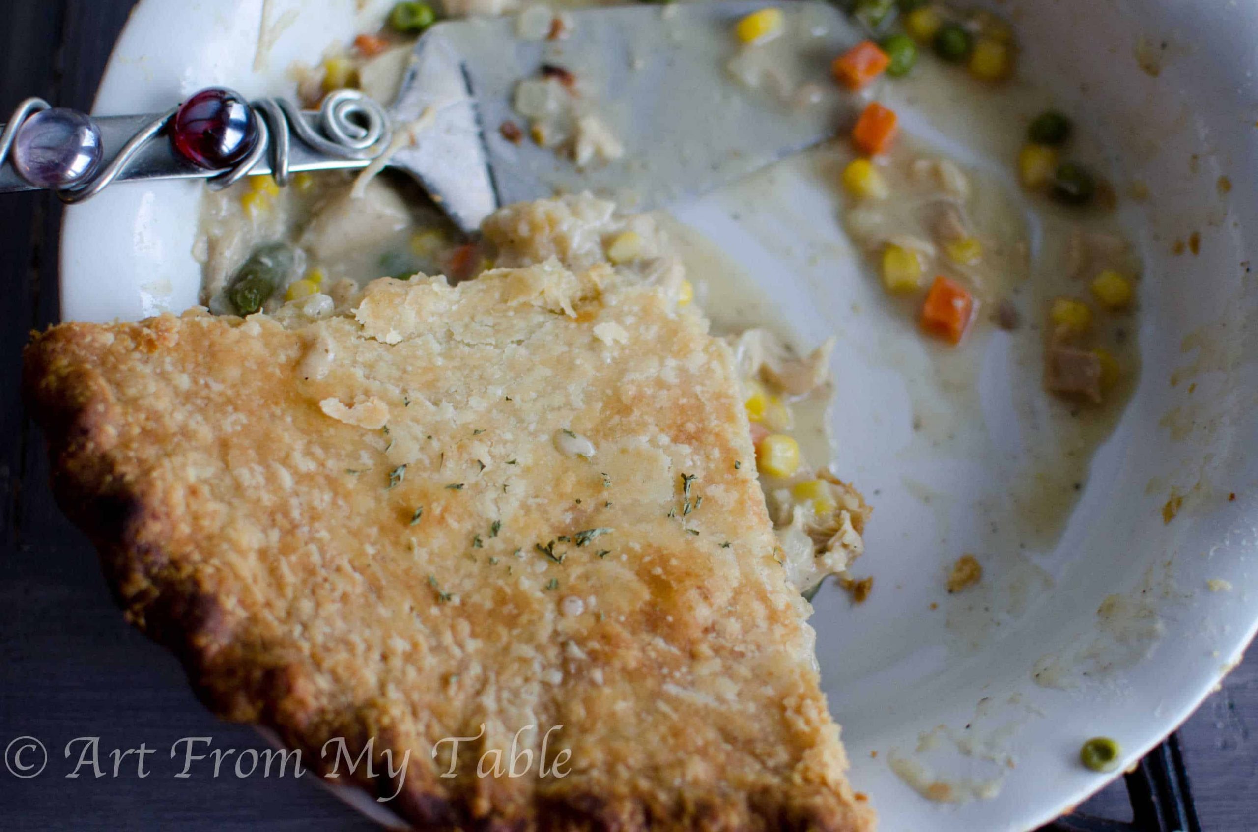 Pie plate with one slice of turkey pot pie left in it, with a pretty spatula on the side.