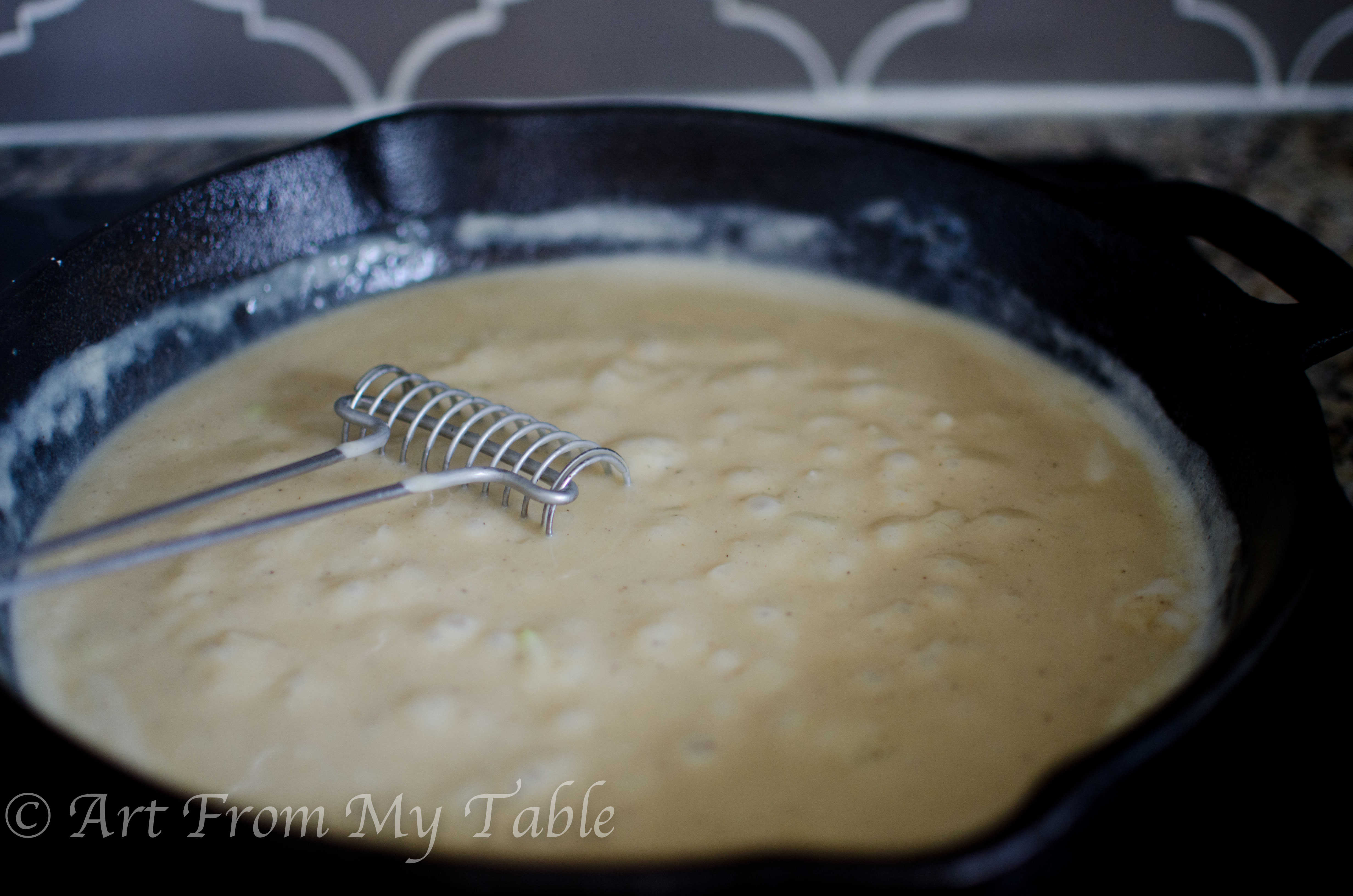 Cast iron skillet with creamy white sauce for turkey pot pie.