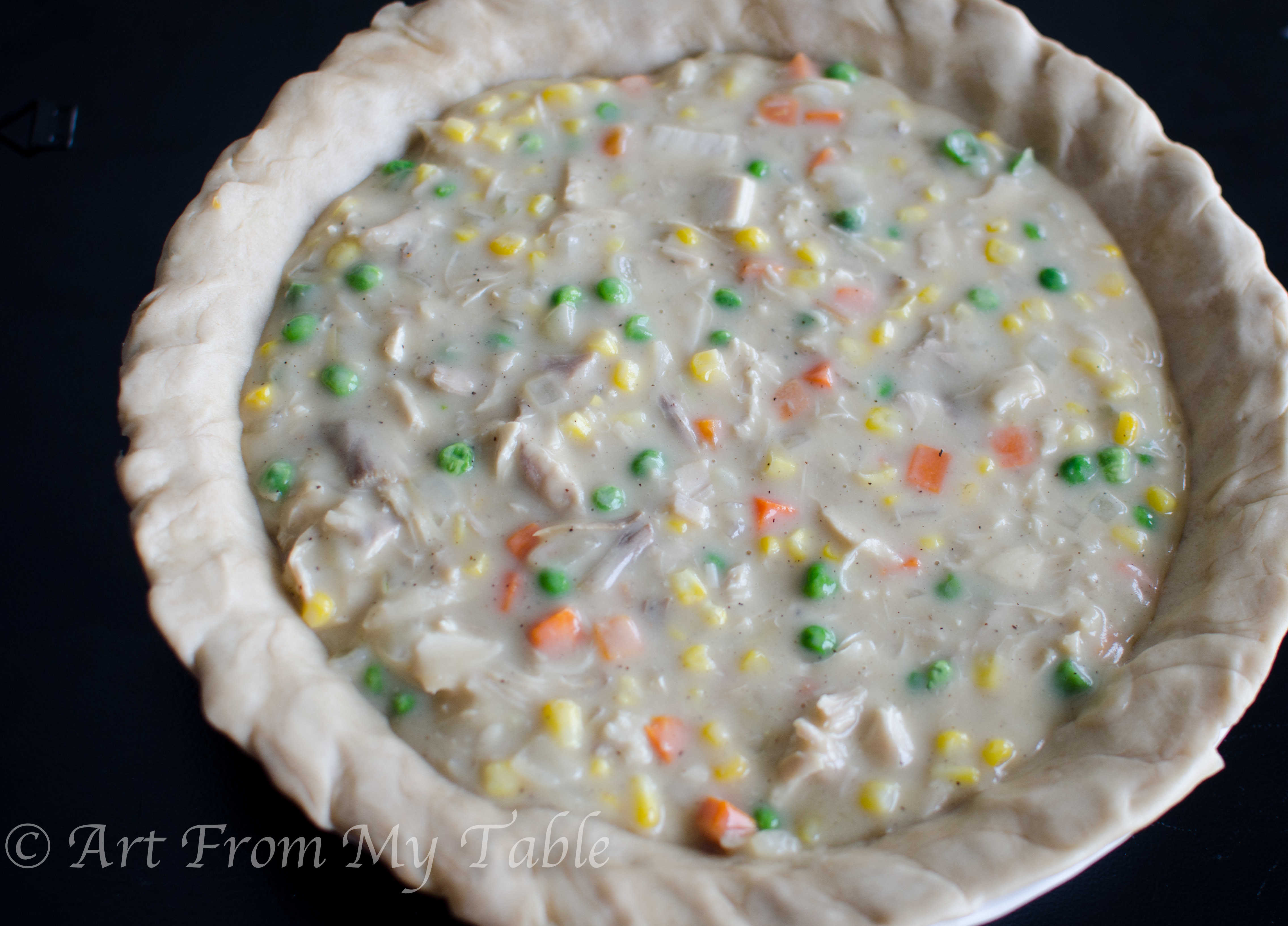 Turkey pot pie filling poured into the crust of a pie pan.