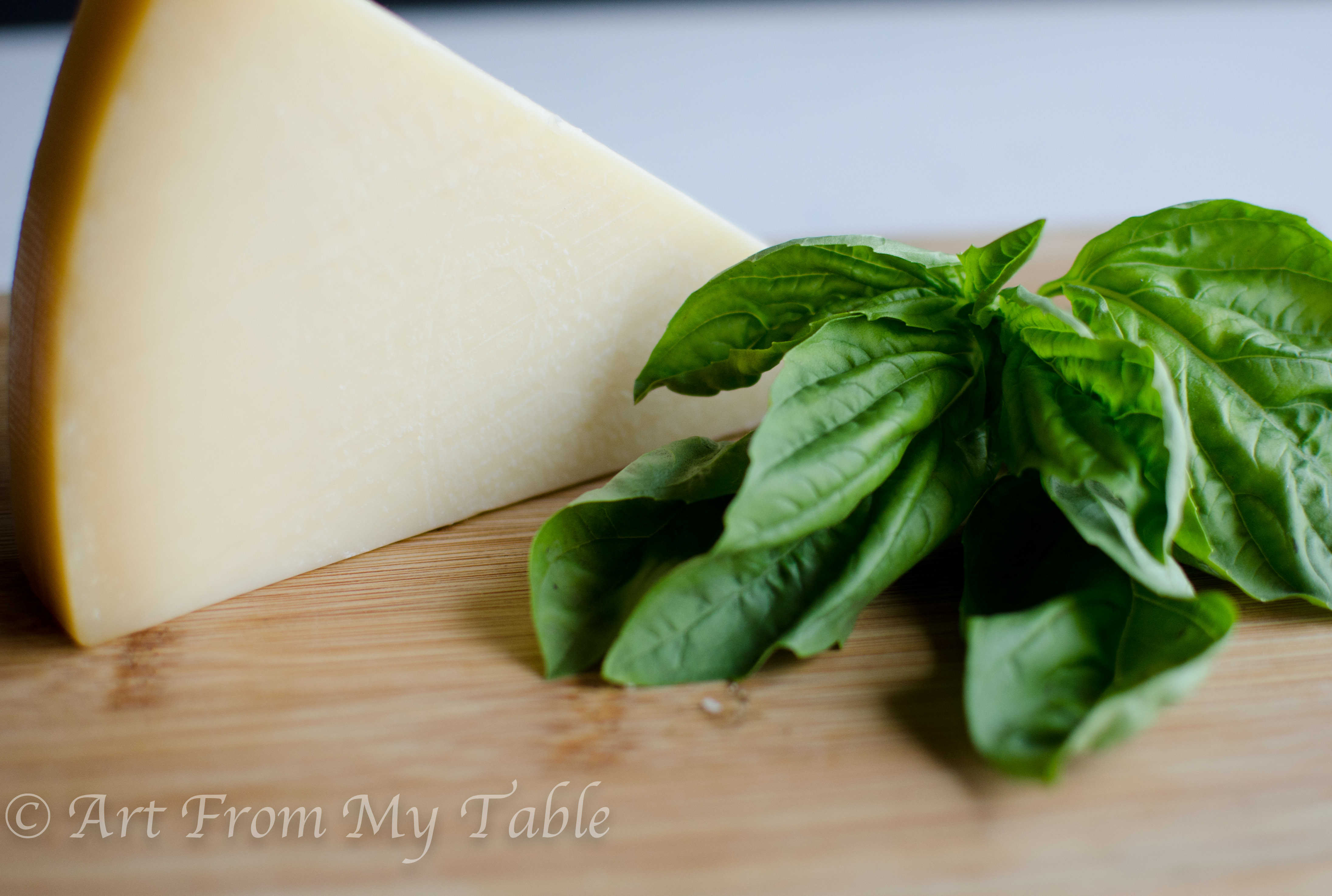 Ingredients for homemade parmesan cheese crisps, Parmesan cheese and fresh basil leaves.