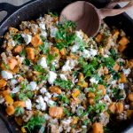 turkey skillet dinner: wooden spoon, ground turkey, diced sweet potato, kale and goat cheese in a cast iron skillet