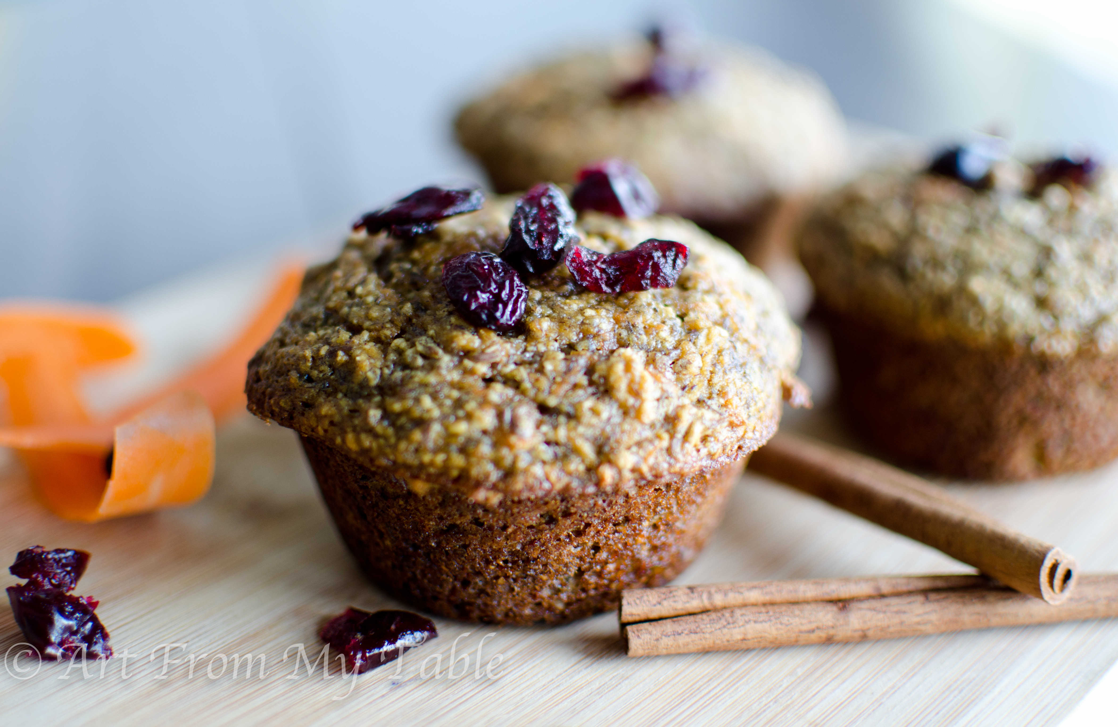 Bran flax muffins with a couple of cinnamon sticks and craisins next to it.