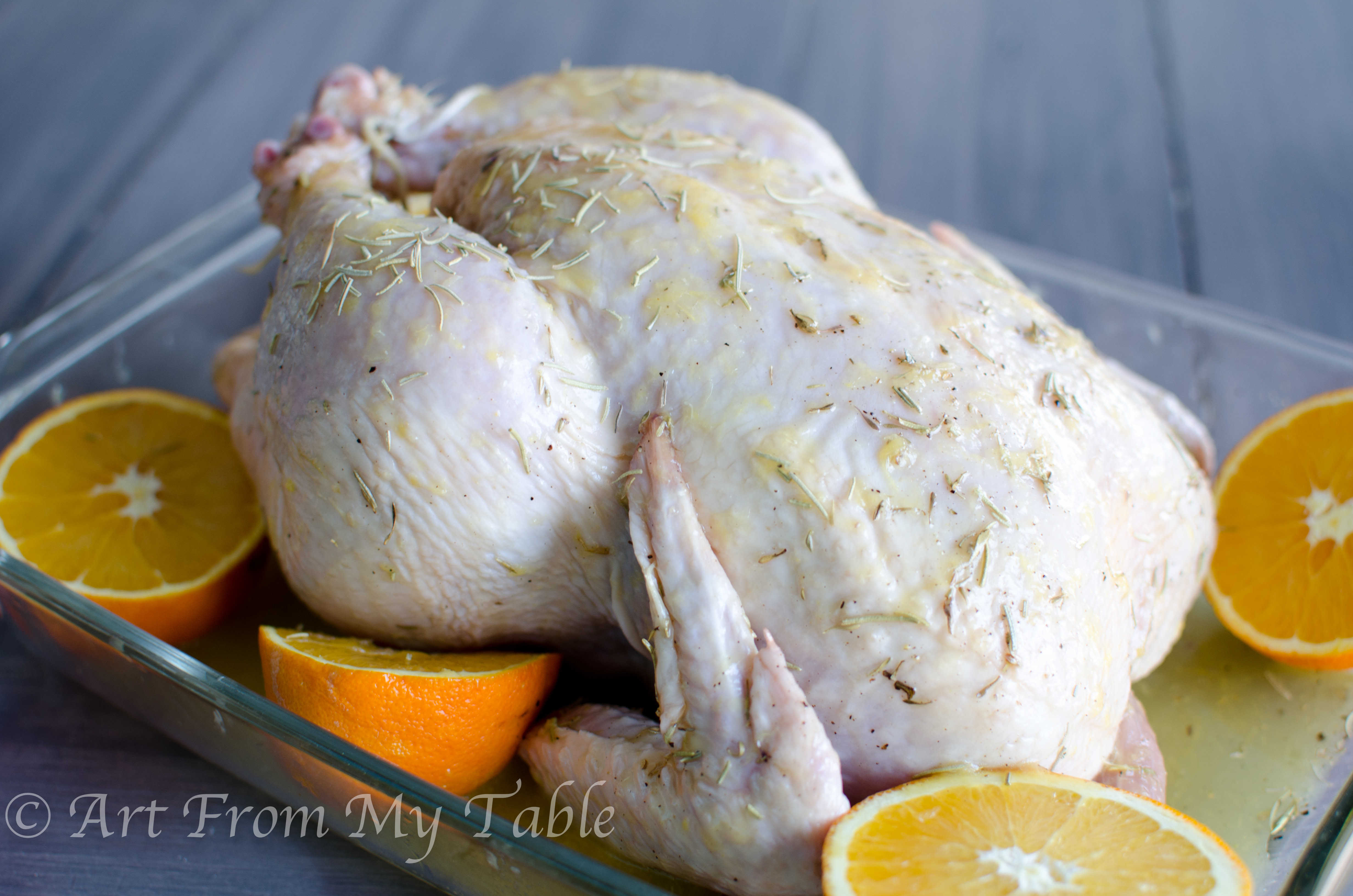 Uncooked whole chicken with seasonings and orange glaze on it. 