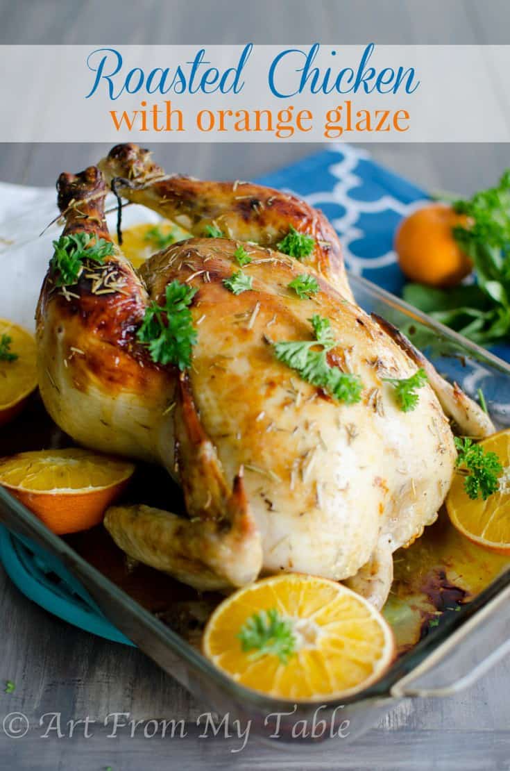 Whole roasted chicken with orange glaze  garnished with parsley and orange slices. 