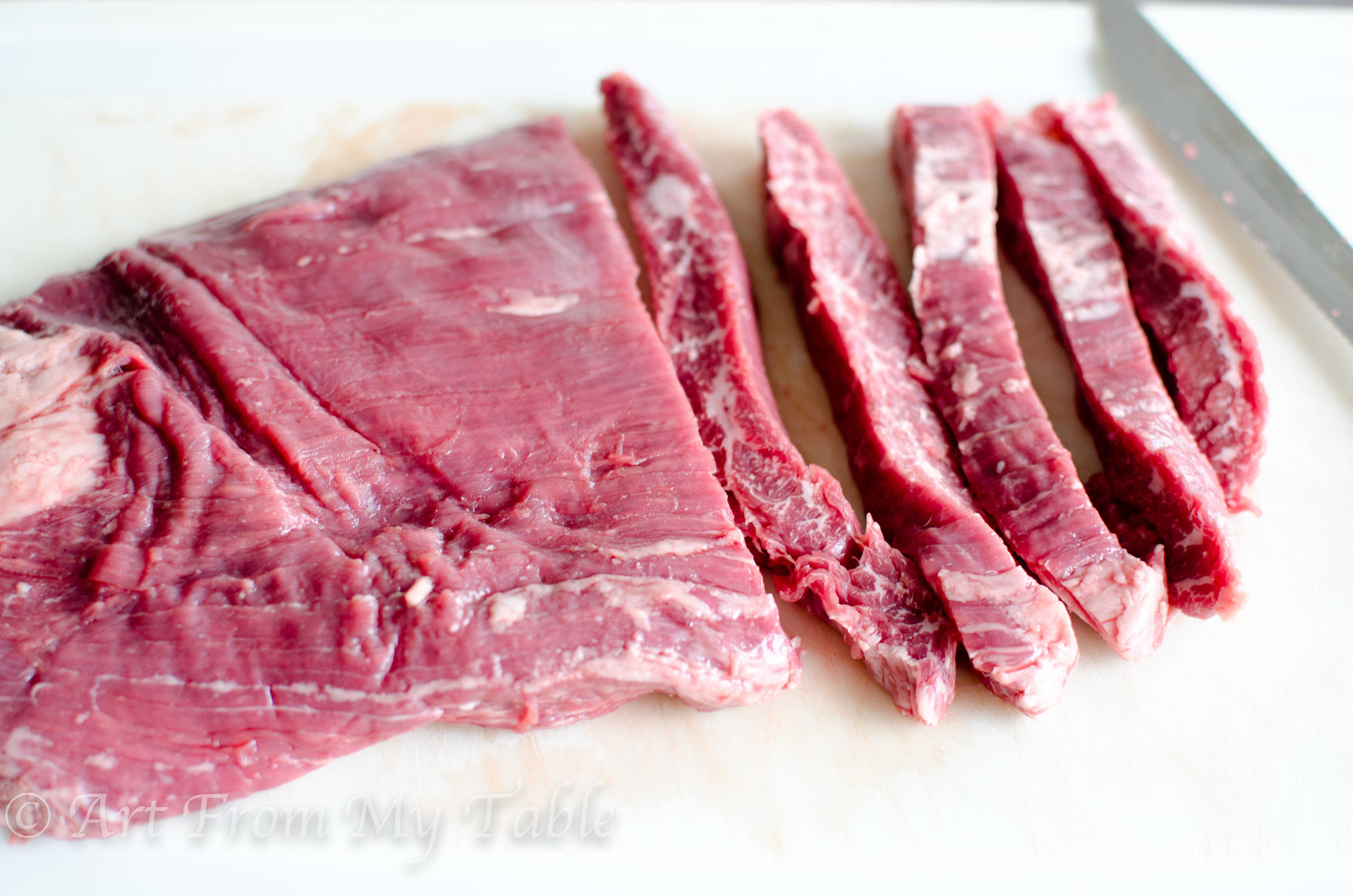 Raw flank steak, partially sliced into ½ inch slices.