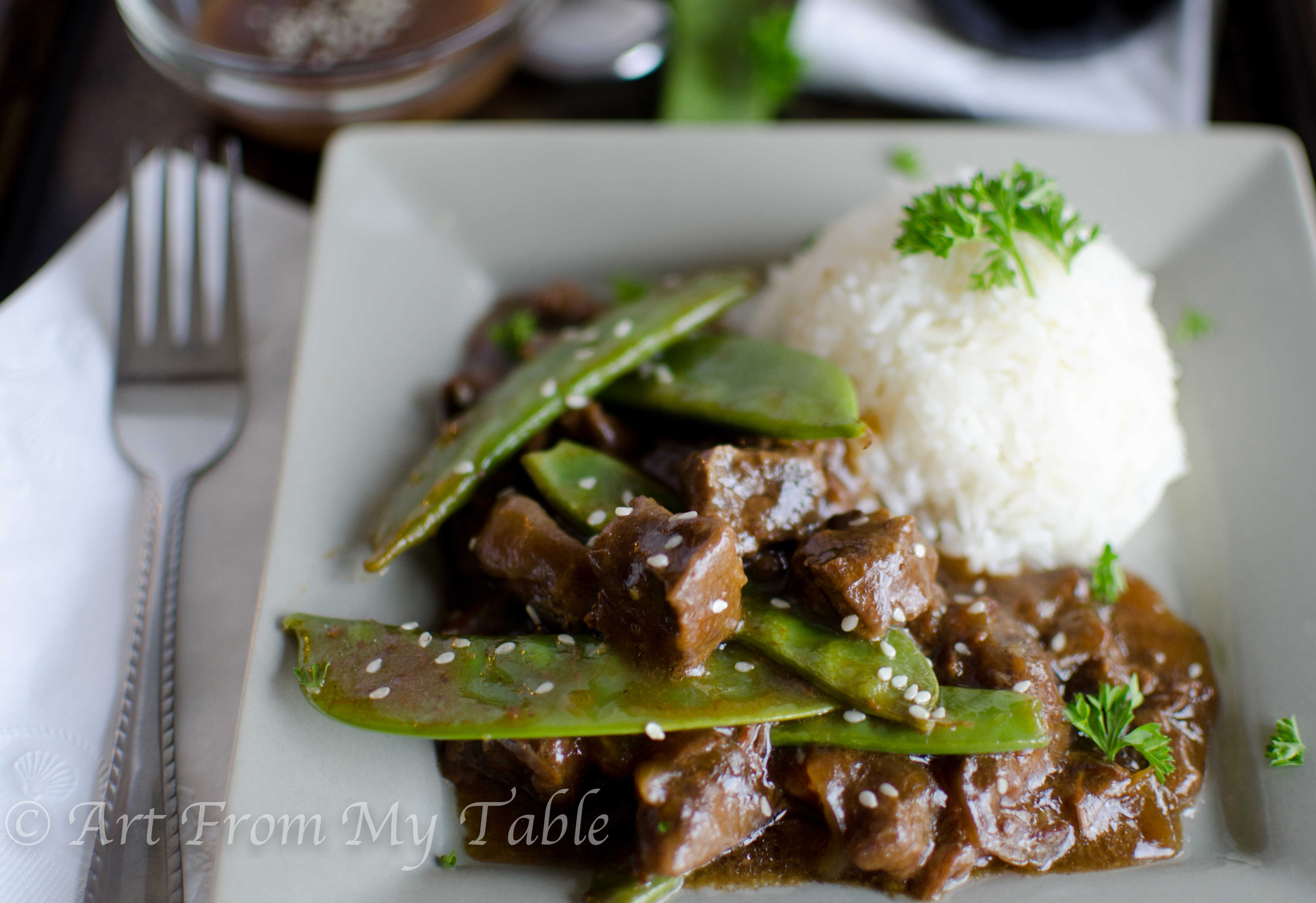 Plate of homemade Beef with Pea pods made in the slow cooker, served with rice. 
