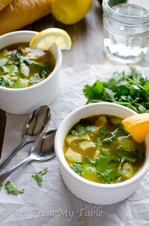 Two bowls of Citrus chicken soup with orange and lemon slices. Cilantro sprinkled on top.