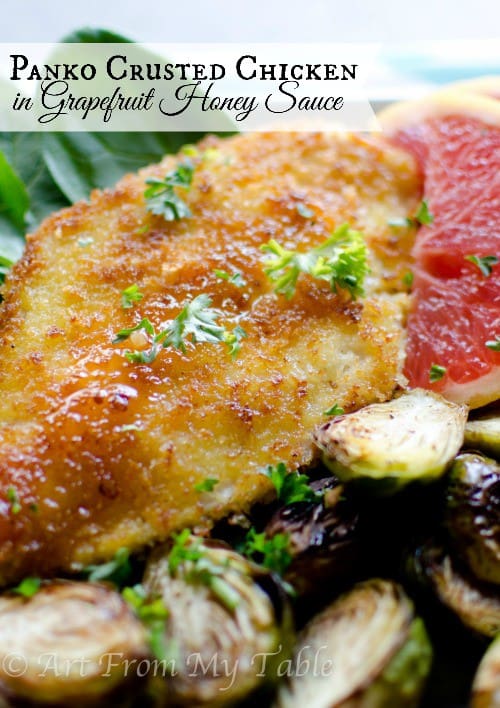 Panko crusted chicken breasy with grapefruit honey sauce on a plate with brussels sprouts.