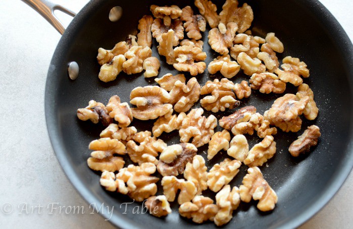 Walnuts being toasted in a small frying pan. 
