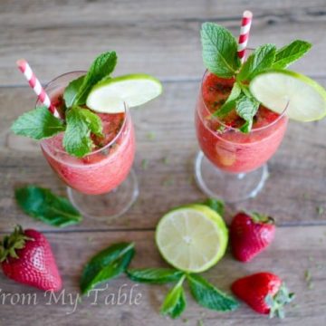 two strawberry mojito mocktails garnished with fresh lime and mint