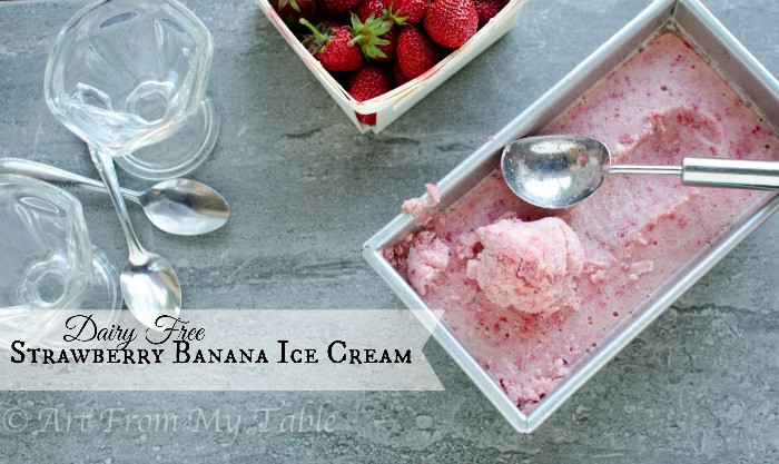 No churn dairy free strawberry banana ice cream in a loaf pan with a scoop, next to dessert glasses and strawberries.