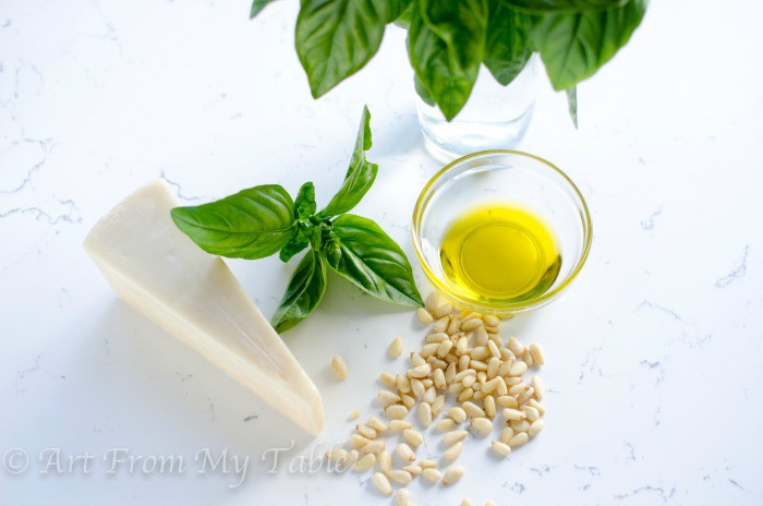 Ingredients for pesto sauce: fresh basil, olive oil, parmesan cheese, pine nuts.
