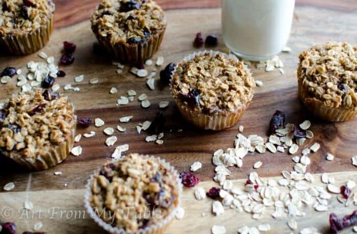 Baked Cranberry Oatmeal cups on a board with a glass of milk.