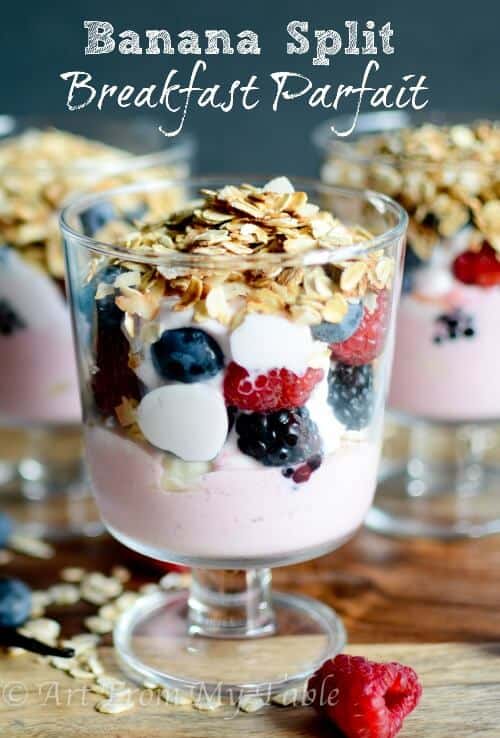 Layered Banana split breakfast parfait in a glass topped with toasted oats. 