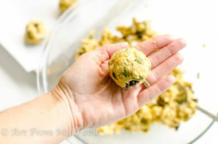 Hand holding Pumpkin cookie dough formed into a ball.