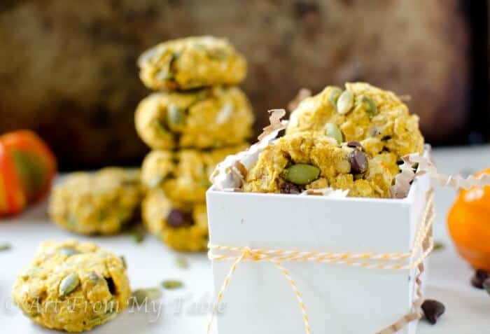 Pumpkin breakfast cookies in a white gift box, stack of cookies in the background.
