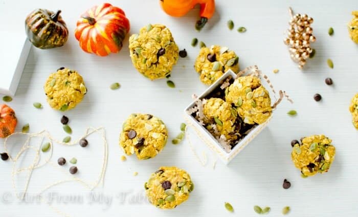 Pumpkin breakfast cookies on a table with gourds, Pepitos, and chocolate chips.