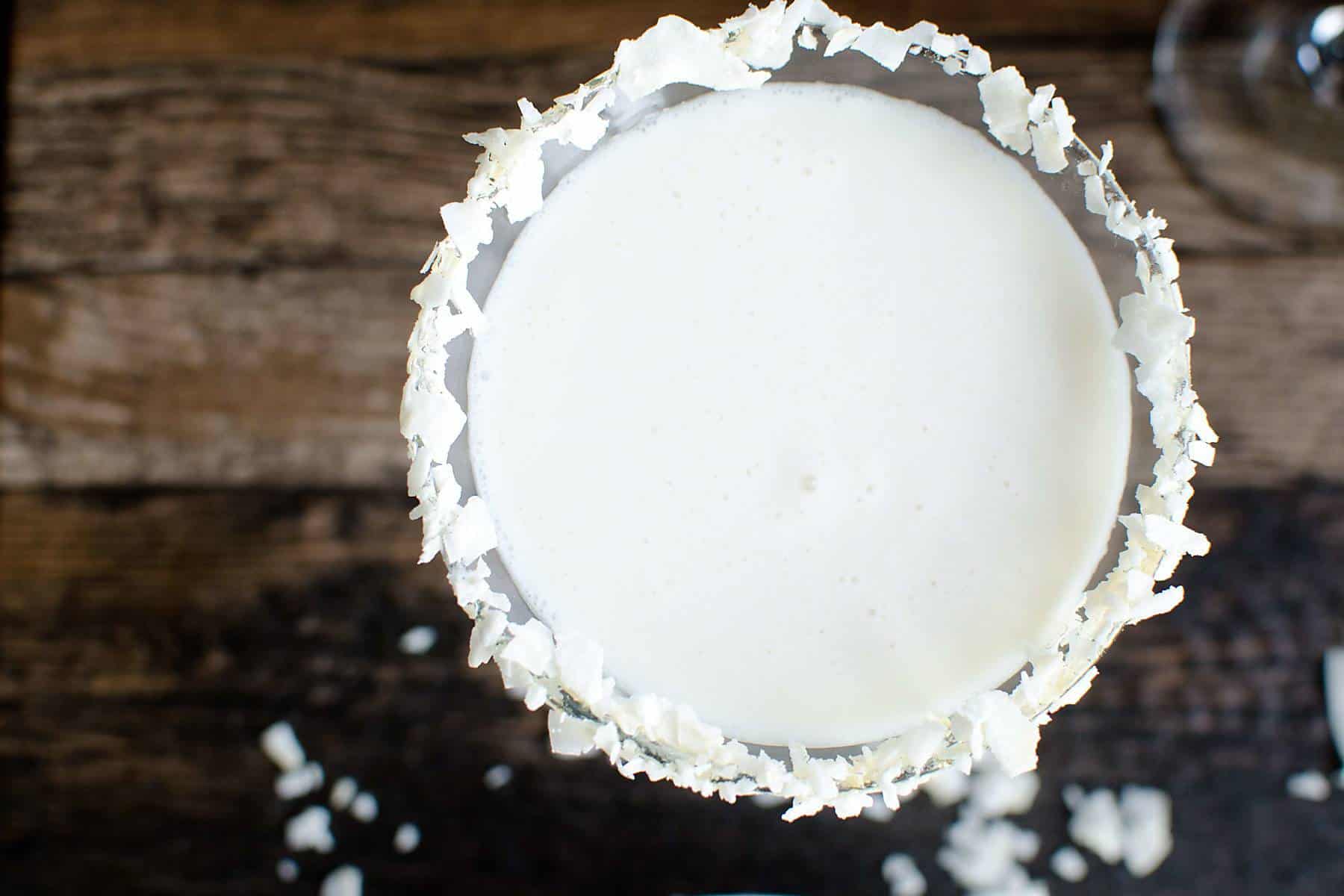 Top view of Coconut Cream "Mocktini" in a martini glass rimmed in coconut flakes.