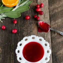 homemade cranberry sauce in a white dish with a spoon full of sauce