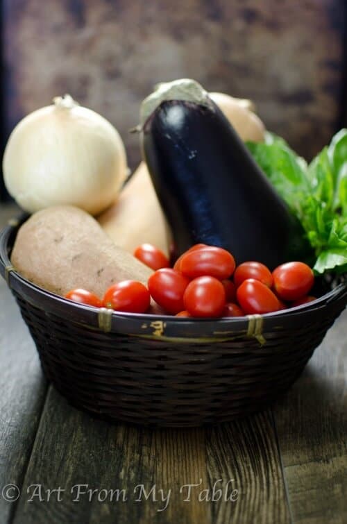 basket of fresh vegetables: onion, butternut squash, sweet potato, eggplant and tomatoes.