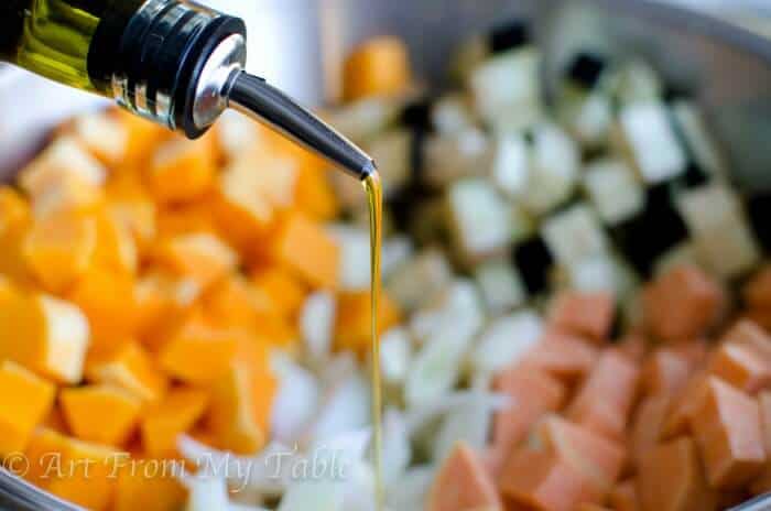 Olive oil being poured onto diced vegetables. 