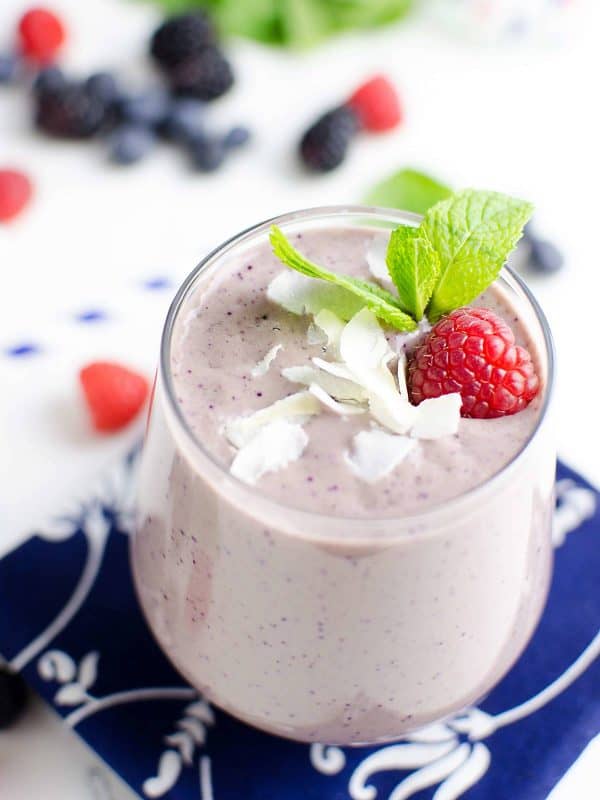 berry blast smoothie garnished with a raspberry, coconut chips and a mint leaf.