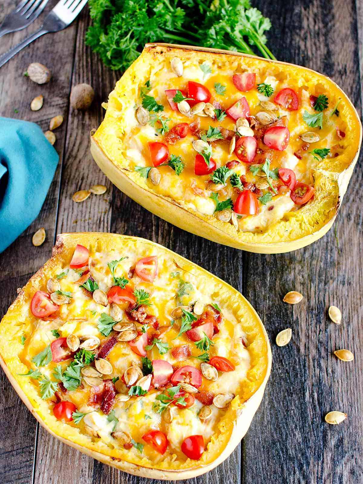 Cooked spaghetti squash loaded with cheese, spinach, and seasoning served in the shell of a spaghetti squash garnished with tomatoes, parsley, and toasted squash seeds.