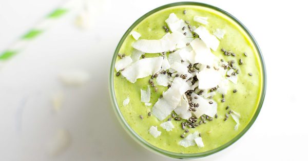 Top view of tropical green smoothie garnished with coconut chips and chia seeds. 