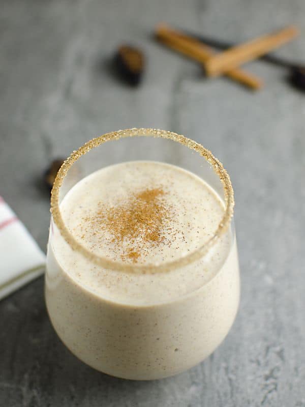 Fig Newton Smoothie on gray counter surrounded with dried figs, vanilla bean and cinnamon sticks