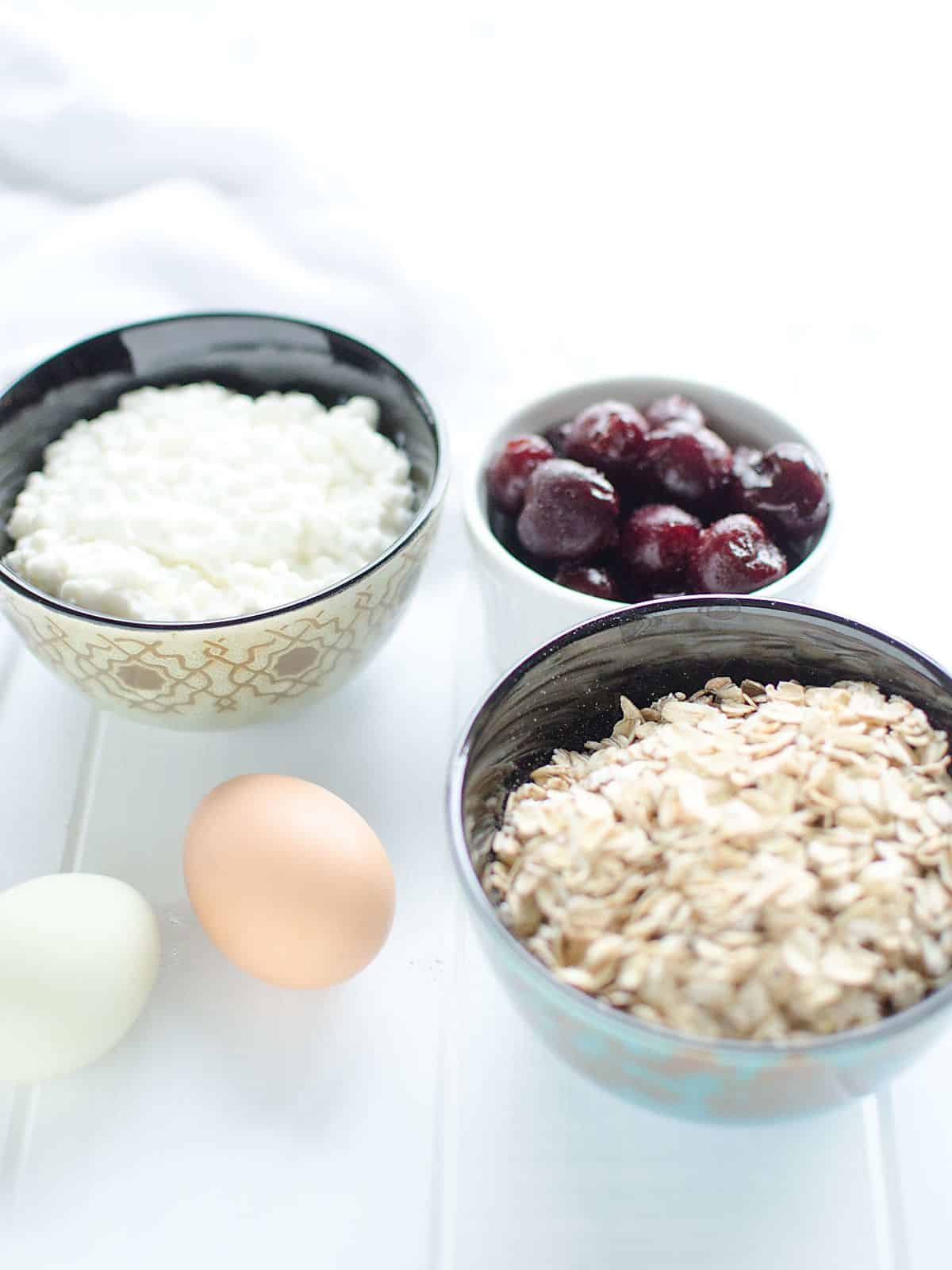 Ingredients for cherry breakfast cake: oatmeal, cottage cheese, frozen cherries, and eggs.