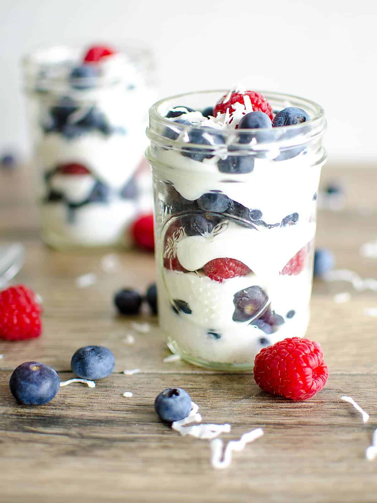 coconut yogurt layered with raspberries and blueberries in a mason jar.
