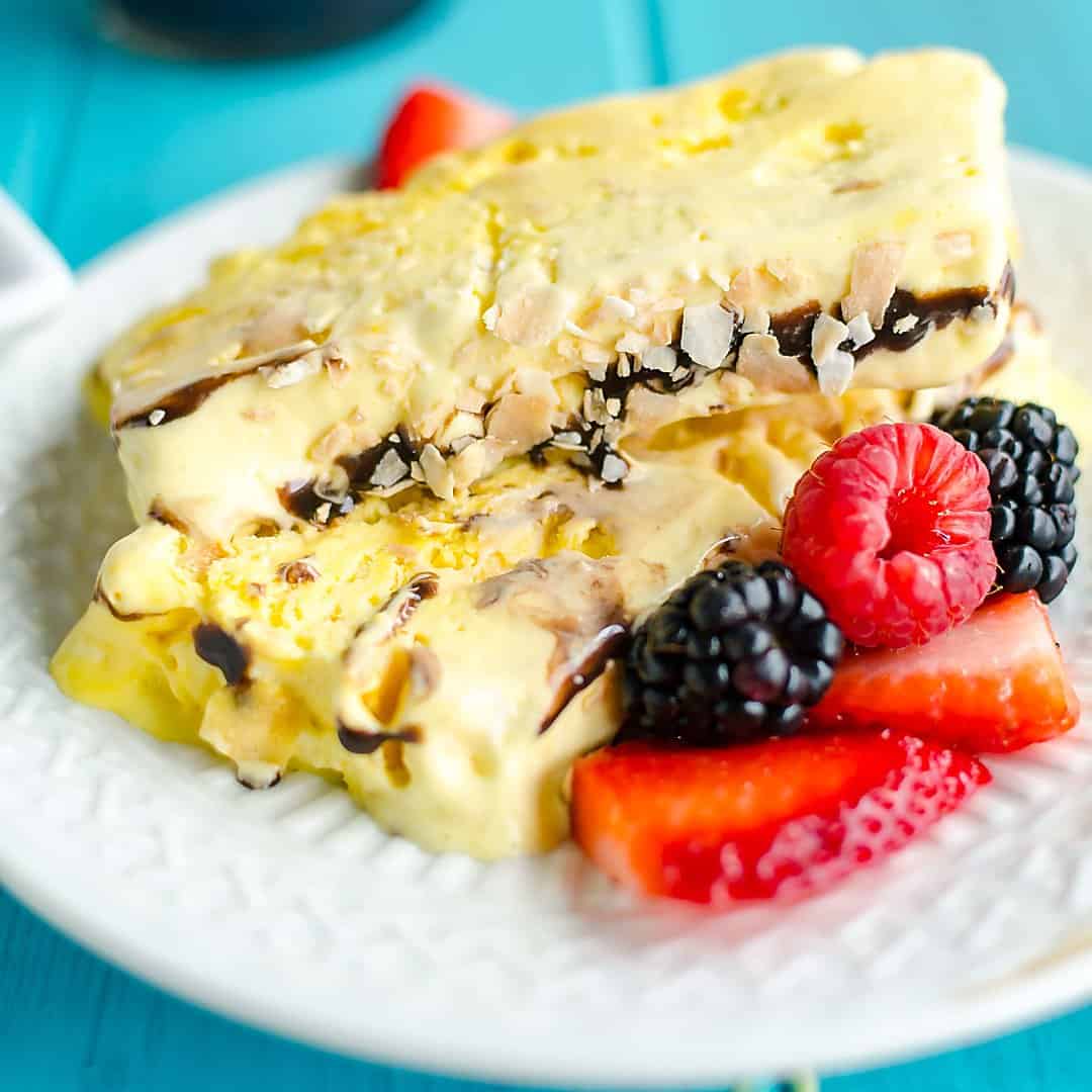 Slices of frozen coconut parfait (ice cream) on a plate garnished with fresh berries.